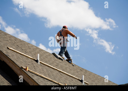 Immigrant Worker Installing Roof Shingles Stock Photo