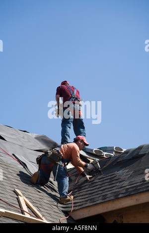 Immigrant Worker Installing Roof Shingles Stock Photo