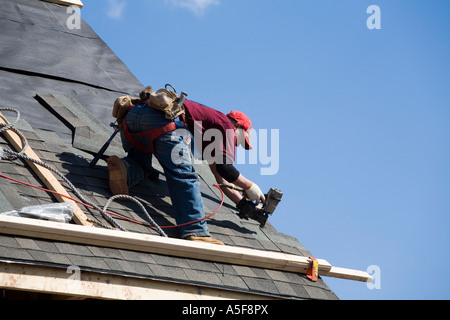 Immigrant Worker Installing Roof Shingles Stock Photo