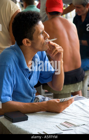 Man smoking a cigarette while playing a game of cards at a park in Rio de Janeiro Brazil Stock Photo