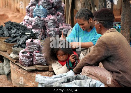 Ambalavao, Madagascar, mother combs daughter's hair while selling coal Stock Photo