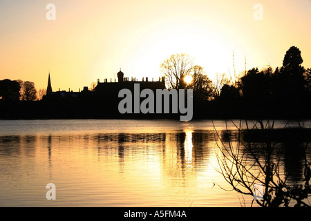 Sunset over the Park Lake, Lurgan with Brownlow House and the town in silhouette, County Armagh, Northern Ireland Stock Photo