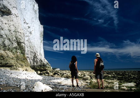 Couple walking on beach beneath chalk cliffs Cuckmere Haven Seven Sisters Country Park Cliff End Eastbourne East Sussex England Stock Photo
