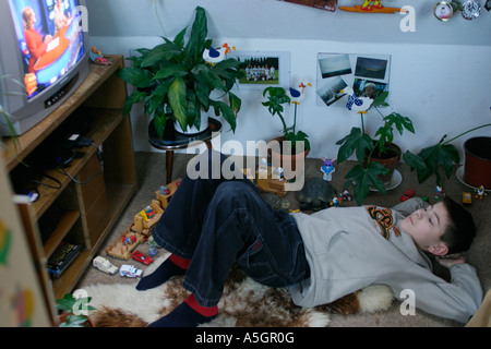 young boy lying on the floor of his room watching television Stock Photo