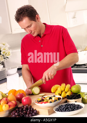 MAN IN KITCHEN CUTTING FRUIT Stock Photo
