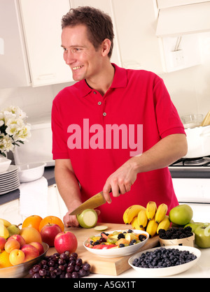 MAN IN KITCHEN CUTTING FRUIT Stock Photo