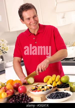 MAN IN KITCHEN CUTTING FRUIT Stock Photo