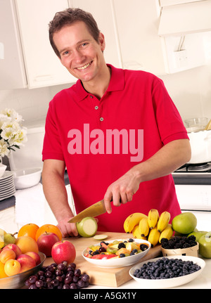 MAN IN KITCHEN CUTTING FRUIT Stock Photo