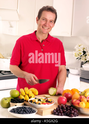 MAN IN KITCHEN CUTTING FRUIT Stock Photo