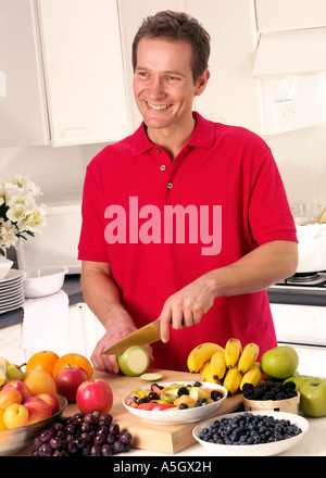 MAN IN KITCHEN CUTTING FRUIT Stock Photo