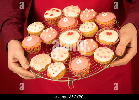 MAN HOLDING COOLING RACK FULL OF CUP CAKES OR FAIRY CAKES Stock Photo