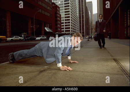 Businessman doing push ups in street Stock Photo