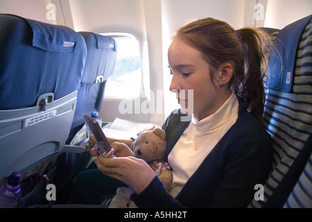 Young girl playing with Game Boy electronic toy traveling on  holiday. Stock Photo