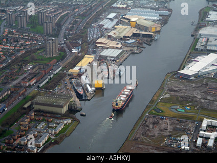 Ship being escorted up the river Clyde, Glasgow February 2007, past frigates under construction at Clyde Shipbuilders Stock Photo