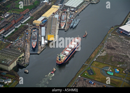 Ship being escorted up the river Clyde, Glasgow February 2007, past frigates under construction at Clyde Shipbuilders Stock Photo