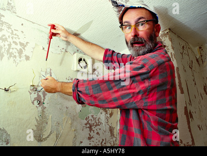 MR PR handyman do it yourselfer renovating a flat holding an electric cable and looking silly Stock Photo