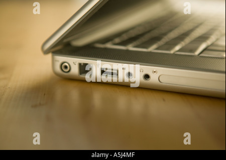 View of side sockets on a metallic cased apple laptop computer lies on a wooden table surface February 2006 Stock Photo