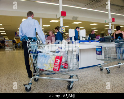 Interior of Tesco Extra supermarket store retail business checkout area toilet rolls in trolley 3 rolls free of charge special offer London England UK Stock Photo
