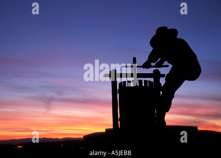 The iconic 15 foot high Grape Crusher Statue on Highway 29 silhouetted by a colorful sunset sky in Napa Valley Wine Country in Northern California. Stock Photo
