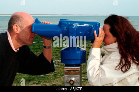 MR lovers walking at seacoast looking together in a telescope Stock Photo