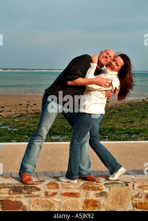MR lovers walking at seacoast in joyful embracement Stock Photo