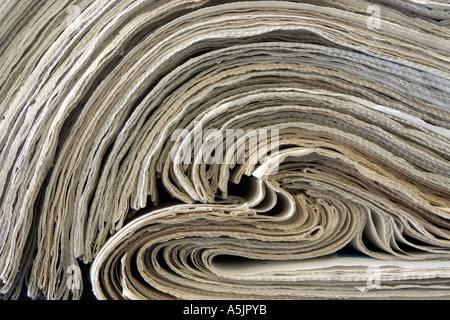 stack of old newspapers rolled back on themselves Stock Photo