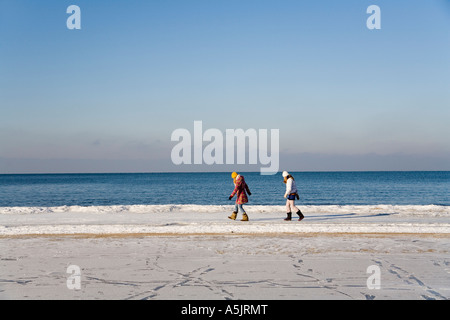 Two female are walking behind each other at the sea, J&#363;rmala , near Riga, in the winter, Latvia, Europe Stock Photo