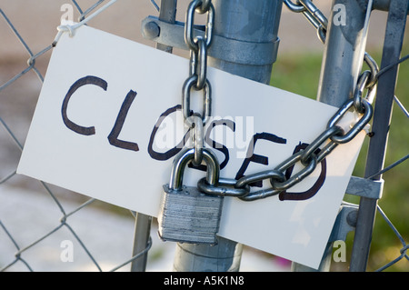 closeup fish eye view of padlock and chain link fence at power substation and CLOSED sign Stock Photo