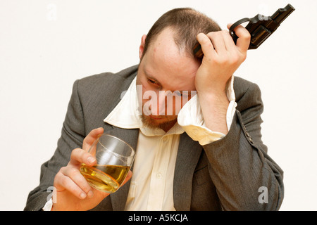 Depression - sad business man is thinking about his life and suicide holding whiskey glas and gun in his hands Stock Photo
