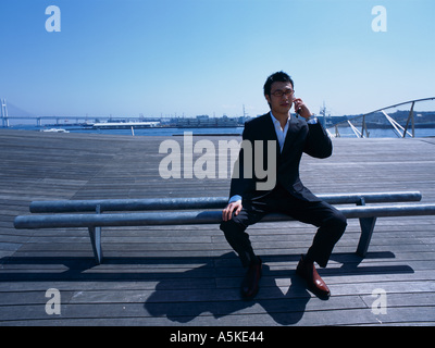 Asian Man on a pier talking on his cell phone Stock Photo