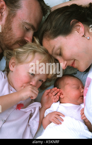 A set of parents are snuggled up tight with their newborn baby girl and young two year old daughter Stock Photo