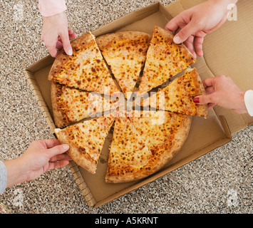 People talking slices of pizza from box Stock Photo