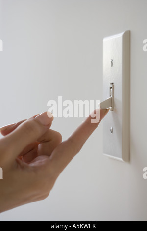 Close up of woman turning on light switch Stock Photo