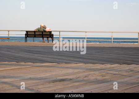 Couple relaxing on boardwalk Rockaway Beach New York City USA Stock Photo