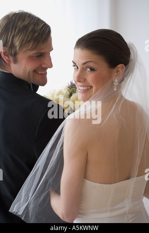 Portrait of bride and groom looking over shoulders Stock Photo