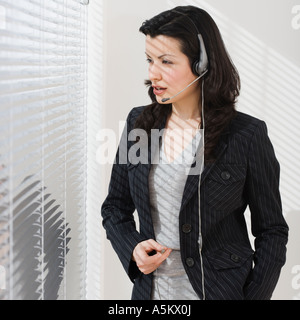 Businesswoman using headset next to window Stock Photo