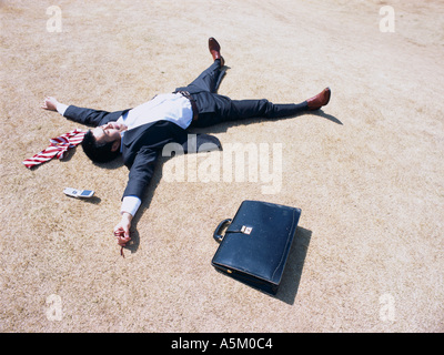 Asian Businessman lying flat on the ground Stock Photo