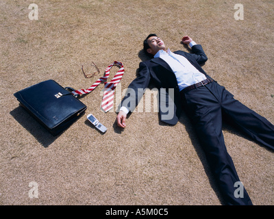 Asian Businessman lying flat on the ground Stock Photo