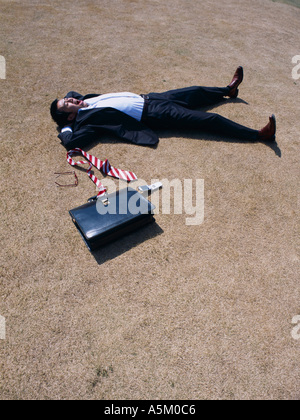 Asian Businessman lying flat on the ground Stock Photo