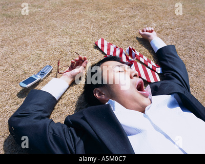 Asian Businessman lying flat on the ground Stock Photo