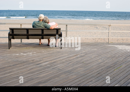 Senior couple relaxing on a park bench by the sea Stock Photo