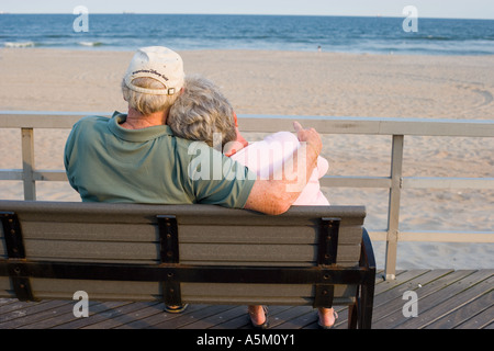 Senior couple relaxing on a park bench by the sea Stock Photo