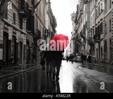 Man walking down a back street in Rome with a Red Umbrella after a rain shower Rome Italy Stock Photo