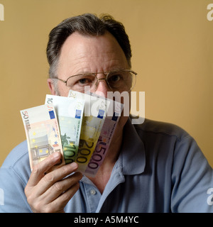 MR MATURE MAN HOLDING EURO BANKNOTES IN FRONT OF HIS FACE Stock Photo