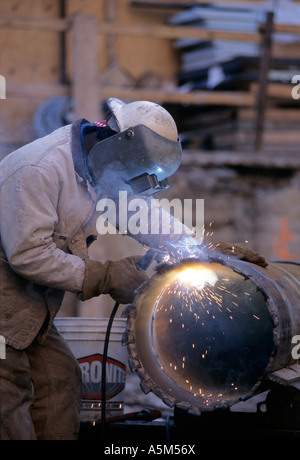 Welder welds drill bit on massive caisson pipe at Random House building in New York  City Stock Photo