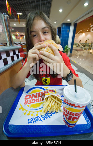 Teenage boy eating a Burger King hamburger Stock Photo