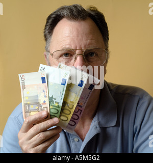 MR MATURE MAN HOLDING EURO BANKNOTES IN FRONT OF HIS FACE Stock Photo