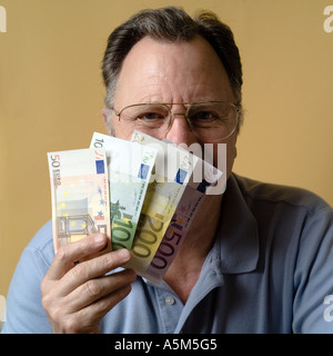 MR MATURE MAN HOLDING EURO BANKNOTES IN FRONT OF HIS FACE Stock Photo