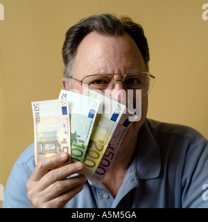 MR MATURE MAN HOLDING EURO BANKNOTES IN FRONT OF HIS FACE Stock Photo
