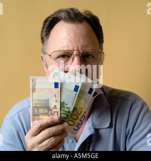MR MATURE MAN HOLDING EURO BANKNOTES IN FRONT OF HIS FACE Stock Photo